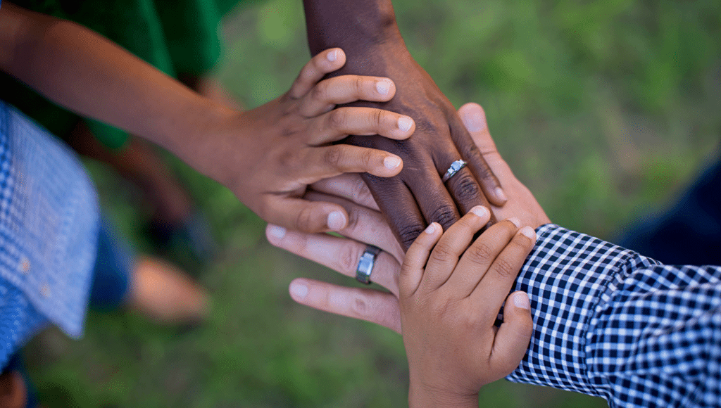 Hands of a diverse blended family stacked together in a show of unity and support.